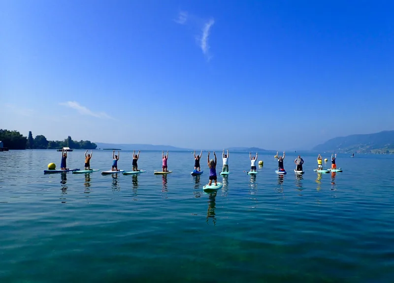 Eine Gruppe übt Yoga auf Stand-up-Paddle-Boards auf dem See, blauer Himmel
